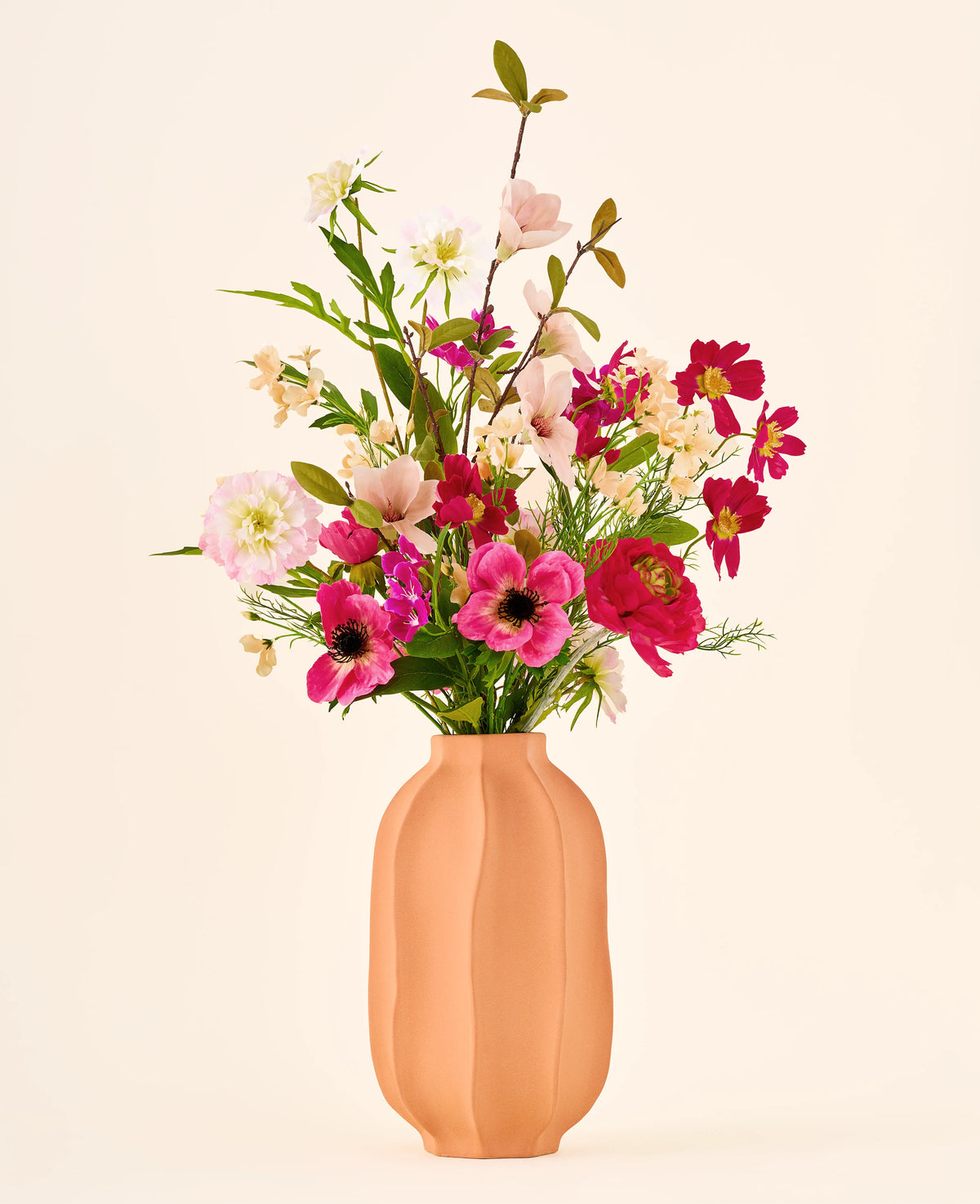 Zijden kunstbloemenboeket Blossom Bliss met een mix van roze en rode bloemen in een geribbelde perzikkleurige vaas.
