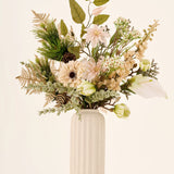 Zijden kunstbloemenboeket Golden Winter, bestaande uit kunstbloemen, bladgroen en een dennenappel in een geribbelde, gebroken witte vaas.