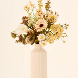 Zijden kunstbloemenboeket Latte Macchiato met crèmekleurige, witte en bruine bloemen in een hoge, geribbelde, gebroken witte vaas.