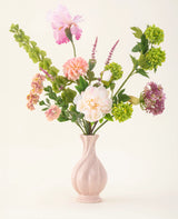 Het Zijden kunstbloemen boeket First Light heeft witte, roze, groene en paarse bloemen met groene bladstelen in een pastelroze vaas - een elegant accent voor elke ruimte.