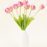 De Zijden kunstbloemen boeket Franse Tulp roze is gerangschikt in een witte vaas, met roze Franse tulpen en groene bladeren tegen een eenvoudige lichte achtergrond.