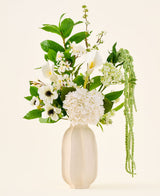 In een witte keramische vaas staat het boeket ‘Green Elegance’ van Zijden kunstbloemen, een arrangement van witte hortensia’s, calla’s, anemonen, groene bladeren en hangend groen tegen een effen lichte achtergrond.