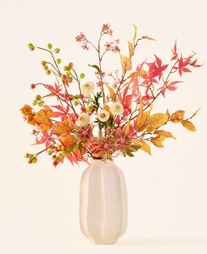 Zijden kunstbloemenboeket ‘Autumn Breeze’ in een witte keramische vaas, met een arrangement van herfstbladeren, kleine groene besjes, roze bloemen en witte bloemen, vervaardigd uit hoogwaardige zijden bloemen. Geplaatst tegen een lichte achtergrond – het perfecte kunstbloemenboeket om elke ruimte langdurig een seizoenssfeer te geven.