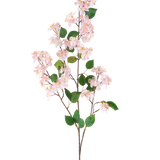 De Kunstbloem Perzikbloesem 140 cm roze is een kunsttak met lichtroze perzikbloesem bloemen en groene bladeren op slanke bruine stelen, afgebeeld geïsoleerd tegen een witte achtergrond.