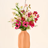 Zijden kunstbloemenboeket Blossom Bliss met een mix van roze en rode bloemen in een geribbelde perzikkleurige vaas.