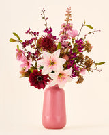 Een boeket van roze, bordeauxrode en witte Zijden kunstbloemen, het boeket Burgundy Dream, in een geribbelde roze vaas.