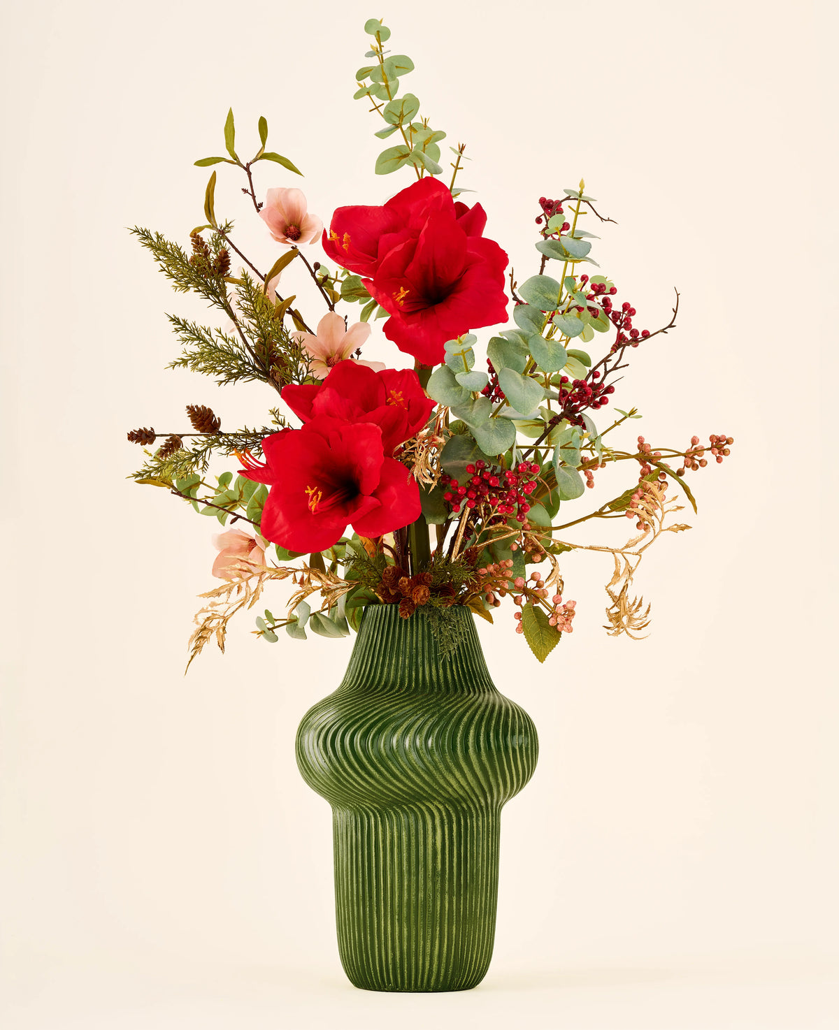 Zijden kunstbloemenboeket Christmas Elegance met rode amaryllis, eucalyptus en bessen in een groene keramische vaas met ribbels.