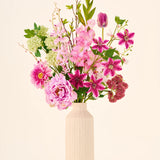 Een onderhoudsvrij boeket Pink Passion van Zijden kunstbloemen, bestaande uit roze en groene kunstbloemen in een geribbelde, gespikkelde keramische vaas.