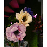 Close-up van de Kunstanemoon Real Touch paars 52cm kunstbloem, verticaal gerangschikt met andere bloemen, tegen een vage achtergrond van groen gebladerte, levendige bloemen en roze neonlichten.