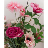 Een close-up van de Kunstroos Real Touch 56 cm roze, een boeket van roze kunstrozen met groene bladeren in een witte vaas, tegen een lichte achtergrond.