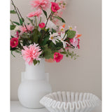 Een witte vaas met een Kunstbloem Rododendron Azalea 73 cm fuchsia staat naast een witte schaal van geribbeld keramiek op een effen ondergrond tegen een neutrale achtergrond.