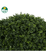 Een close-up van de Kunstplant Buxus op stam romeinse stijl UV 95cm toont dichte, glanzend groene kunstbladeren. Een UV-beschermingssymbool linksboven benadrukt de geschiktheid voor buitengebruik.