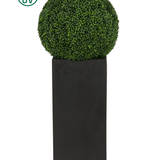 De Kunstplant Buxus romeinse stijl UV D55cm, een ronde kunstvorm, staat in een hoge zwarte plantenbak met een UV-beschermingspictogram in de linkerbovenhoek van de afbeelding.