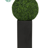 De Kunstplant Buxus romeinse stijl UV D65cm, een ronde kunst buxus vormboom, staat op een hoge rechthoekige zwarte plantenbak met een UV zonwering icoon linksboven tegen een witte achtergrond.