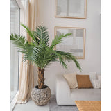 De Kunstpalm Phoenix Canarie 160 cm voegt een tropische sfeer toe naast een lichte bank met neutrale kussens in een moderne woonkamer met abstracte kunst, transparante gordijnen en een geweven salontafel.