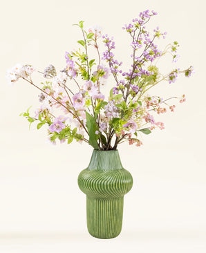 Het Zijden kunstbloemen boeket Lilac heeft een groene, gestructureerde vaas gevuld met roze, witte en lila bloemen plus groene bladeren - een elegant arrangement voor elke omgeving.