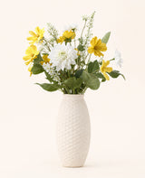Zijden kunstbloemen boeket Sunny Whisper, een elegant boeket van gele en witte zijden bloemen met groene bladeren, gepresenteerd in een witte vaas tegen een lichte achtergrond.