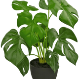 De Kunst Monstera 40 cm in sierpot zwart is een kunstmatige Monstera met grote, glanzend groene bladeren met natuurlijke gaten en scheuren, in een eenvoudige zwarte sierpot gevuld met donkere aarde.