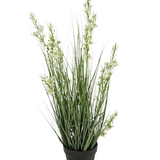 De Kunstgras Gierst Uien graspot 65cm brandvertragend heeft hoge, slanke groene grasachtige bladeren en verschillende stelen met kleine witte bloemen in een zwarte pot, tegen een effen witte achtergrond.
